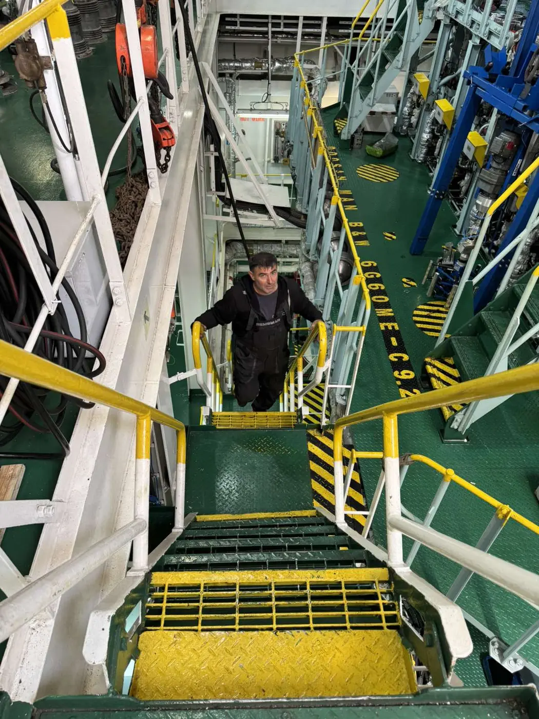 REMSMAR technician on engine room stairs looking toward the camera